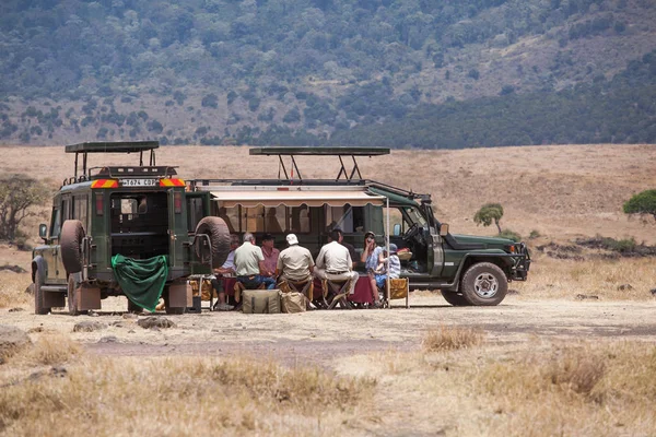 Turistler safari arabalarını yakınındaki bir öğle yemeği
