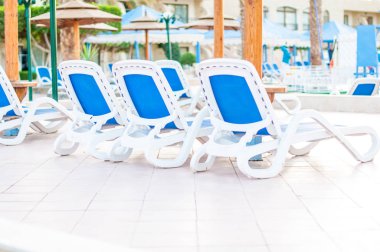 Güzel tropikal plaj ön otel tatil sırasında sıcak güneşli bir gün Yüzme Havuzu, Güneş-şezlong ve palmiye ağaçları ile.