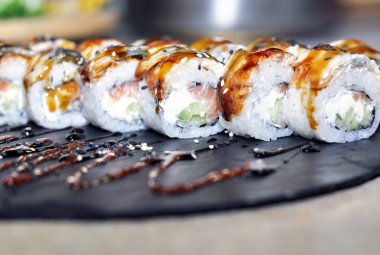 Yılan balığı suşi plastik kutu ambalaj tepsisinde siyah taş arduvaz arka plan üzerine alır.