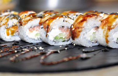 Yılan balığı suşi plastik kutu ambalaj tepsisinde siyah taş arduvaz arka plan üzerine alır.