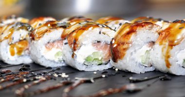 Yılan balığı suşi plastik kutu ambalaj tepsisinde siyah taş arduvaz arka plan üzerine alır.