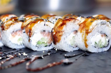 Yılan balığı suşi plastik kutu ambalaj tepsisinde siyah taş arduvaz arka plan üzerine alır.