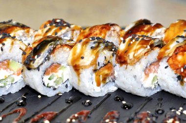 Yılan balığı suşi plastik kutu ambalaj tepsisinde siyah taş arduvaz arka plan üzerine alır.