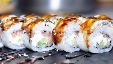 Yılan balığı suşi plastik kutu ambalaj tepsisinde siyah taş arduvaz arka plan üzerine alır.