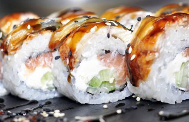 Yılan balığı suşi plastik kutu ambalaj tepsisinde siyah taş arduvaz arka plan üzerine alır.