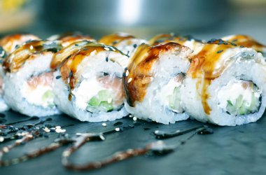 Yılan balığı suşi plastik kutu ambalaj tepsisinde siyah taş arduvaz arka plan üzerine alır.