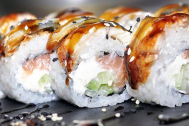 Yılan balığı suşi plastik kutu ambalaj tepsisinde siyah taş arduvaz arka plan üzerine alır.