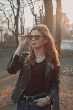 Bir Hollywood gülümseme ve gözlük ile mutlu kız, gün batımı bir parkta yürüyüş