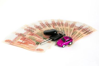 Beyaz arka plan üzerinde para kazanın. Mor oyuncak araba ve para arabanın anahtarları. Faturaları 5 bin ruble, yayılmış bir fan tarihlerde.