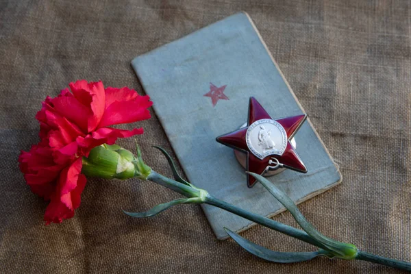 O cravo vermelho, o livro de soldados, a Ordem da Rua Vermelha na tela. Close-up . — Fotografia de Stock