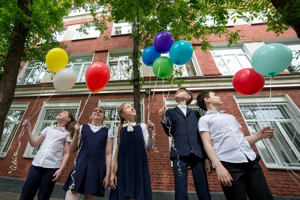 Los escolares con globos en el fondo de los árboles y la — Foto de Stock