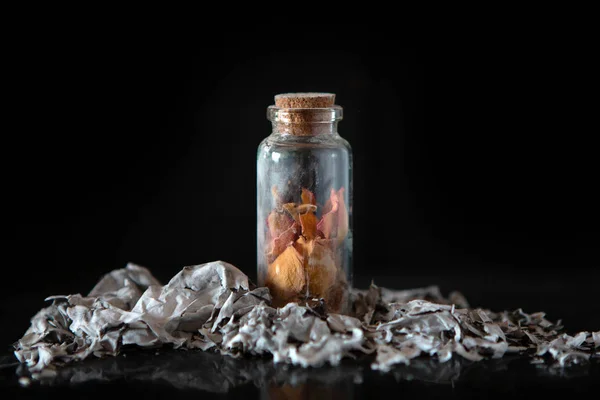 Flasche mit Blütenblättern. Asche auf schwarzem Hintergrund. Erinnerungen — Stockfoto