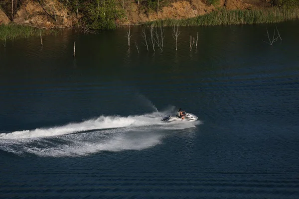 Soleado día de verano, un hombre monta una moto en el lago — Foto de Stock