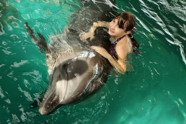 Uma rapariga abraça um golfinho na piscina. Natação com golfinhos, commu — Fotografia de Stock