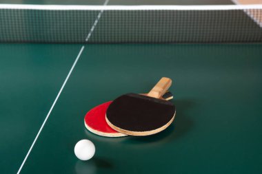 İki masa tenisi raketleri ve yeşil masada bir top. Masa tenisi net