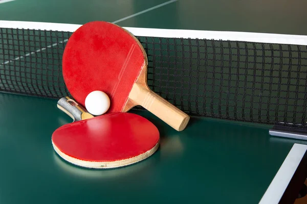 Two ping-pong rackets and a ball on a green table. ping-pong net — Stock Photo, Image