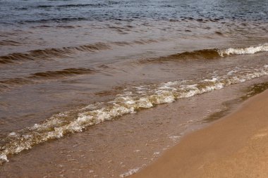 Güneşli bir yaz gününde köpük lü dalgalar. Kumsal