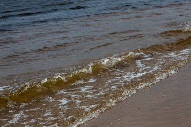 Güneşli bir yaz gününde köpük lü dalgalar. Kumsal