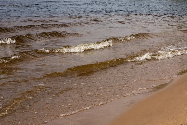 Güneşli bir yaz gününde köpük lü dalgalar. Kumsal