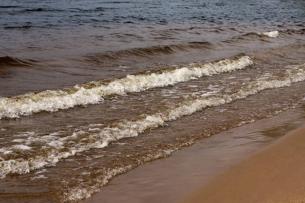 Güneşli bir yaz gününde köpük lü dalgalar. Kumsal