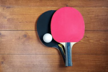 İki ping-pong raketler ve kahverengi ahşap arka planda bir top