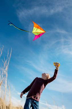 Mavi gökyüzüne karşı uçurtma lı bir çocuk. Parlak güneşli bir gün. Avrupa