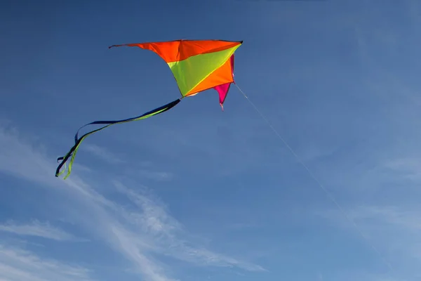 Vliegen met een vlieger. Heldere vlieger tegen de blauwe lucht. Zonnige dag. — Stockfoto