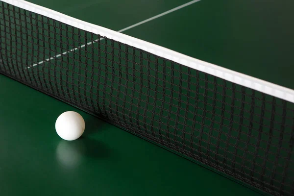 Pingpongový míč na zeleném stole vedle sítě. — Stock fotografie