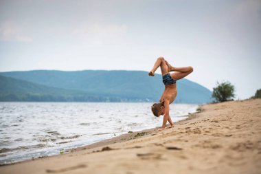 Sahildeki çocuk ellerinin üzerinde yürüyor. Yaz günü