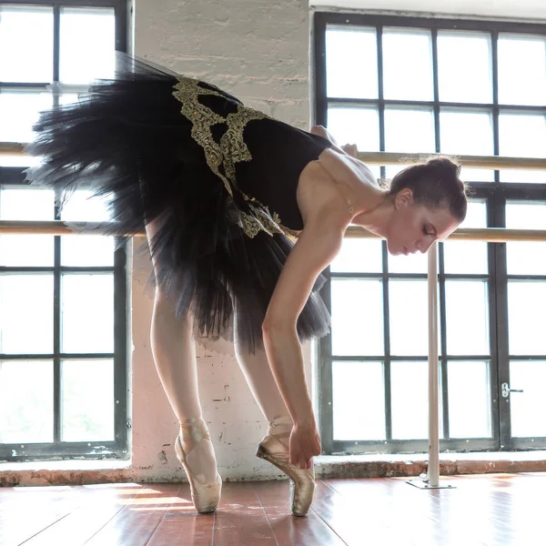 Rehearsal ballerina in the hall. Wooden floor, very large window