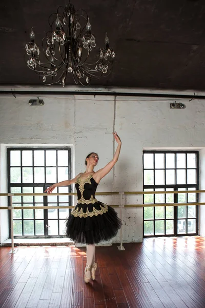 Rehearsal ballerina in the hall. White walls, dark wooden floor