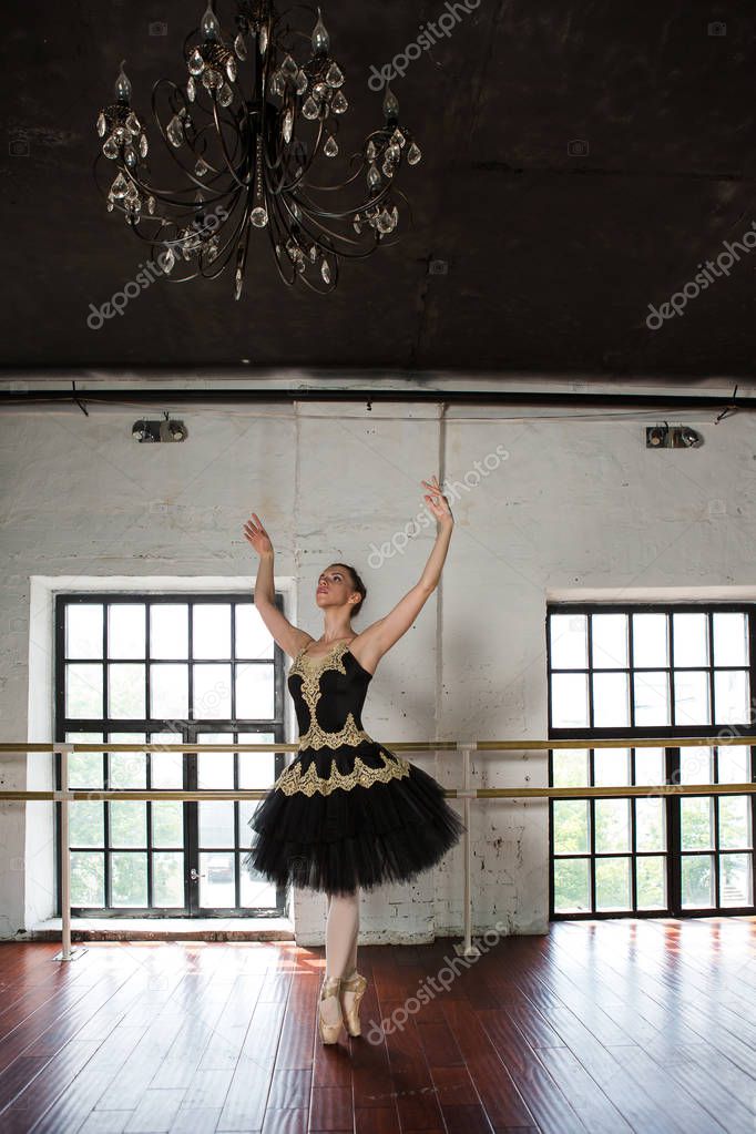 Rehearsal ballerina in the hall. White walls, dark wooden floor 