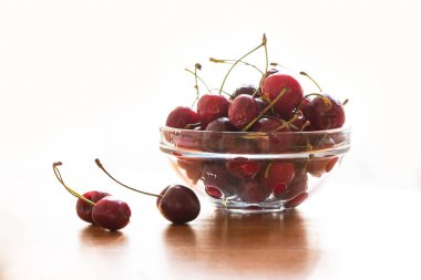 Beyaz bir arka plan üzerinde cam bir tabakta tatlı kiraz. Sulu, lezzetli