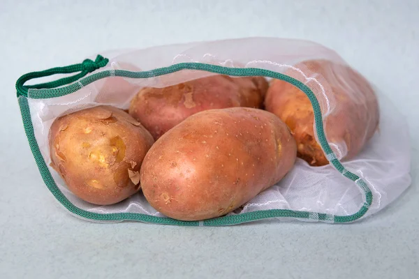 Potatoes in ecological packaging. Reusable bags for vegetables and fruits. Shopping in the store. Eco-friendly packaging. — Stock Photo, Image