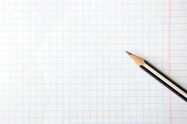 Un lápiz en un cuaderno cuadrado. Copiar espacio. Primer plano . — Foto de Stock
