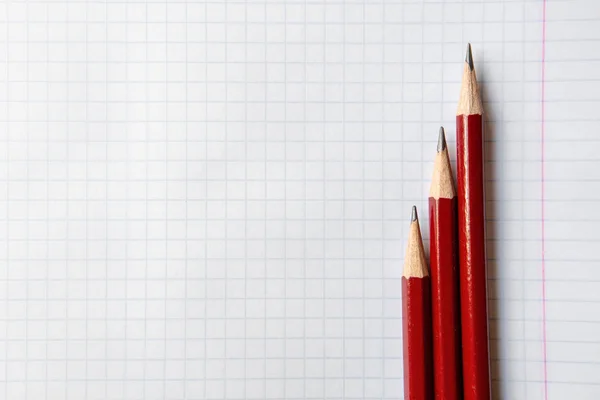 Tre blyertspennor på en fyrkantig anteckningsbok. Kopiera utrymme. Närbild. Stockbild