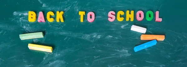 Banner. Inscriptie terug naar school. Stilleven met schoolbenodigdheden. Veelkleurige krijt. Blackboard in krijt schoolbord. Groene achtergrond. Begin van het schooljaar. — Stockfoto