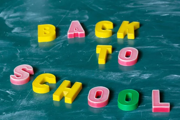 Напис BACK To SCHOOL. Натюрморт з шкільними приладдям. Різнокольоровий крейда. Дошка в крейдяній дошці. Зелений фон. Початок навчального року . — стокове фото