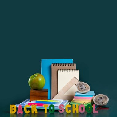 Okula geri yazıt. Okul malzemeleriyle natürmort. Malzemeleri. Yeşil arka plan. Defterler, defterler, keçeli kalemler, renkli kalemler, elma. Renkli resim. 