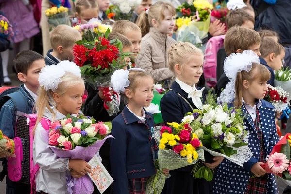 Moskva, Rusko-září, 1, 2015: setkání s žáky první třídy a učitelkou na školním dvoře. Den poznání v Rusku. Děti s květinami. — Stock fotografie