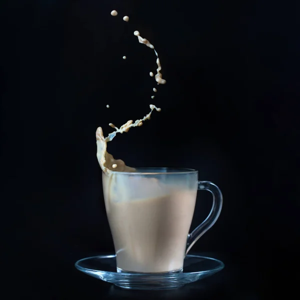 A cup of latte coffee with splash on black background. Spray of coffee. A glass cup — Stock Photo, Image