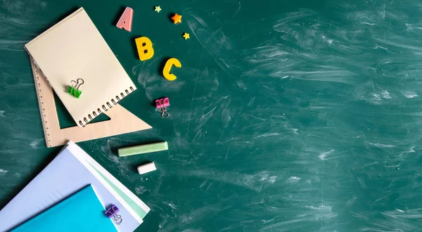 Afiş. Hala okul malzemeleri ile hayat. Tahta tebeşir Chalkboard. Yeşil arka plan. Notebooklar, notebooklar, keçe uçlu kalemler, renkli kalemler. Okul yılı başlangıcı. — Stok fotoğraf
