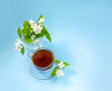 Mavi bir arka plan üzerinde çay ile Fincan. Yasemin çiçek dalları küçük bir buket. 