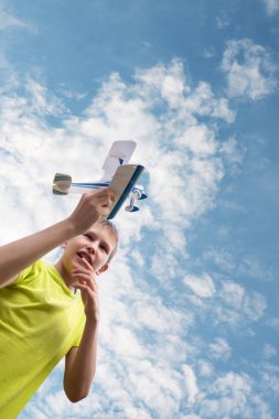 Gökyüzüne karşı bulutları olan bir çocuk. Parlak emoti