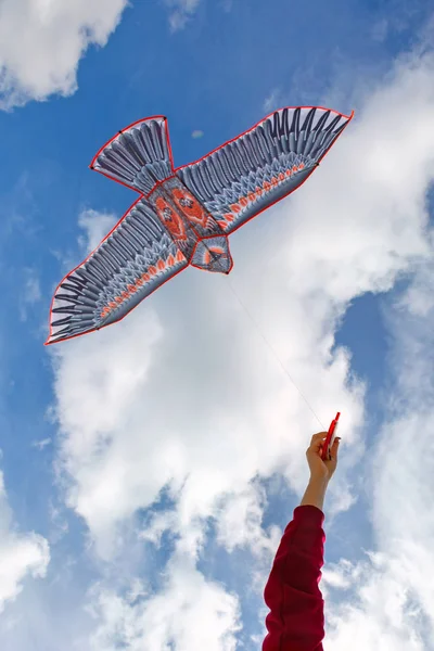 La mano tiene un aquilone. aquilone su uno sfondo di cielo blu con nuvole . — Foto Stock