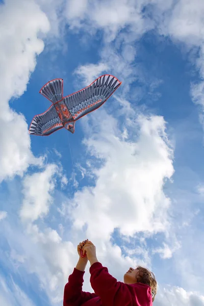 Una ragazza lancia un aquilone. Aquilone volante. Cielo blu con nuvole. Aquilone a forma di aquila . — Foto Stock