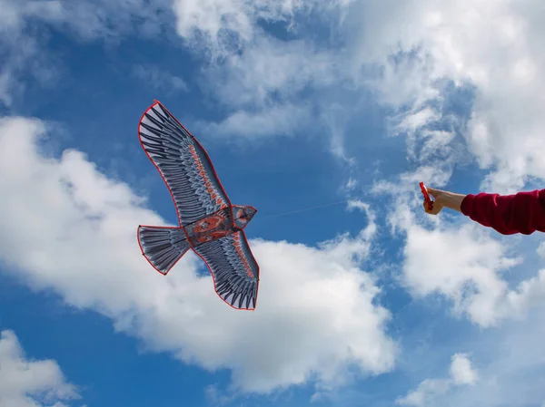 La mano tiene un aquilone. aquilone su uno sfondo di cielo blu con nuvole . — Foto Stock