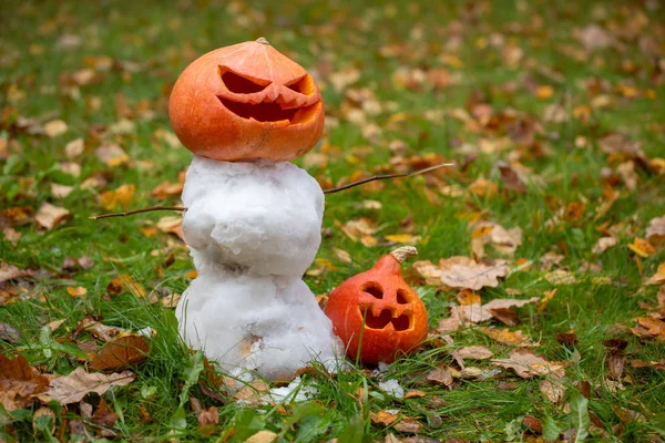 Snögubbe med Jacks huvud på gräsmattan i trädgården. Första snön. Kreativ trädgård dekoration för Halloween. — Stockfoto