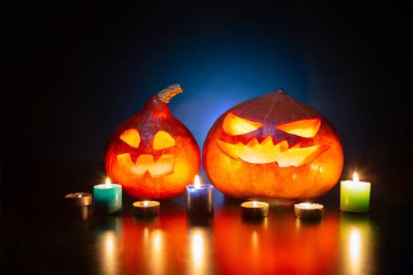 Cadılar Bayramı. Mavi arka planda balkabağı fenerleri. Yakınlarda mumlar var. Cadılar Bayramı.