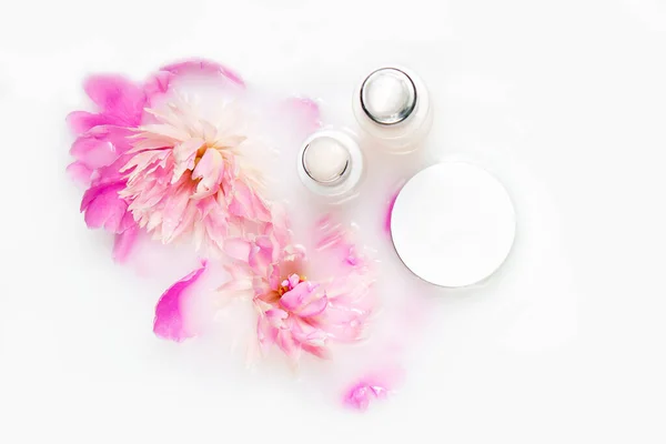 Creams and peony flowers in a bath with milk. Conceptual photo: the best cosmetic tool for body and face care. Tender care. Natural cosmetic.